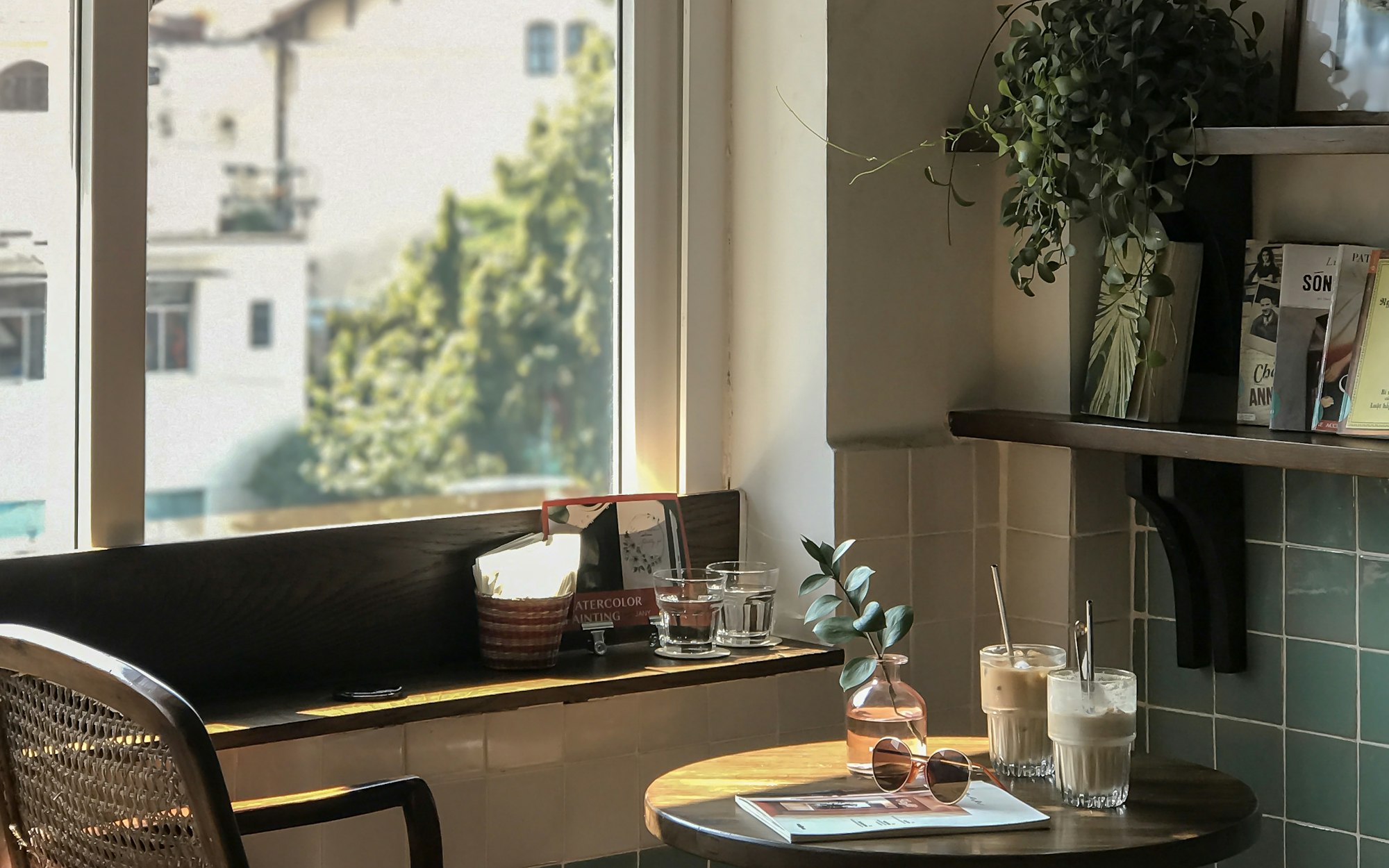 Morning light falling across a corner table at Harbour & Oak, iced lattes and sage-green tiles