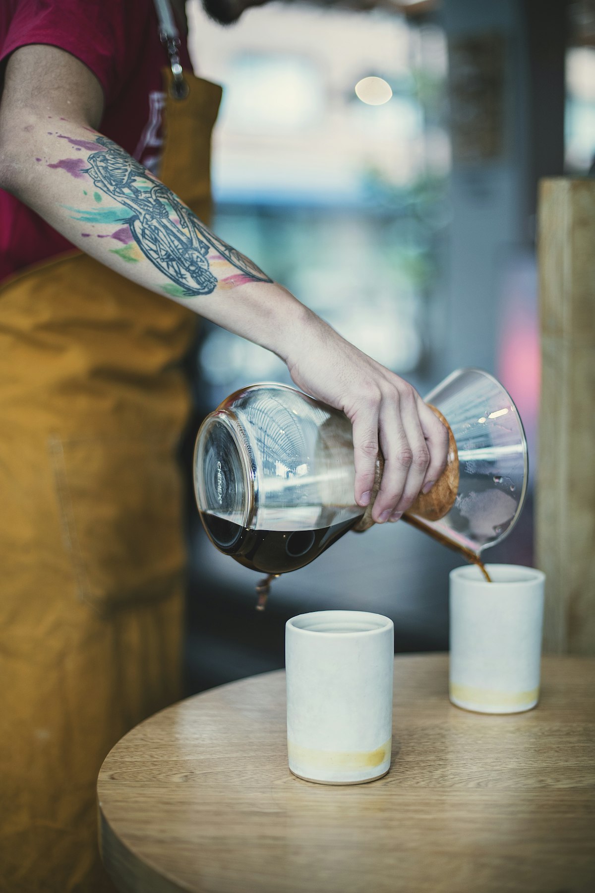 Barista pouring filter coffee from a Chemex into ceramic cups