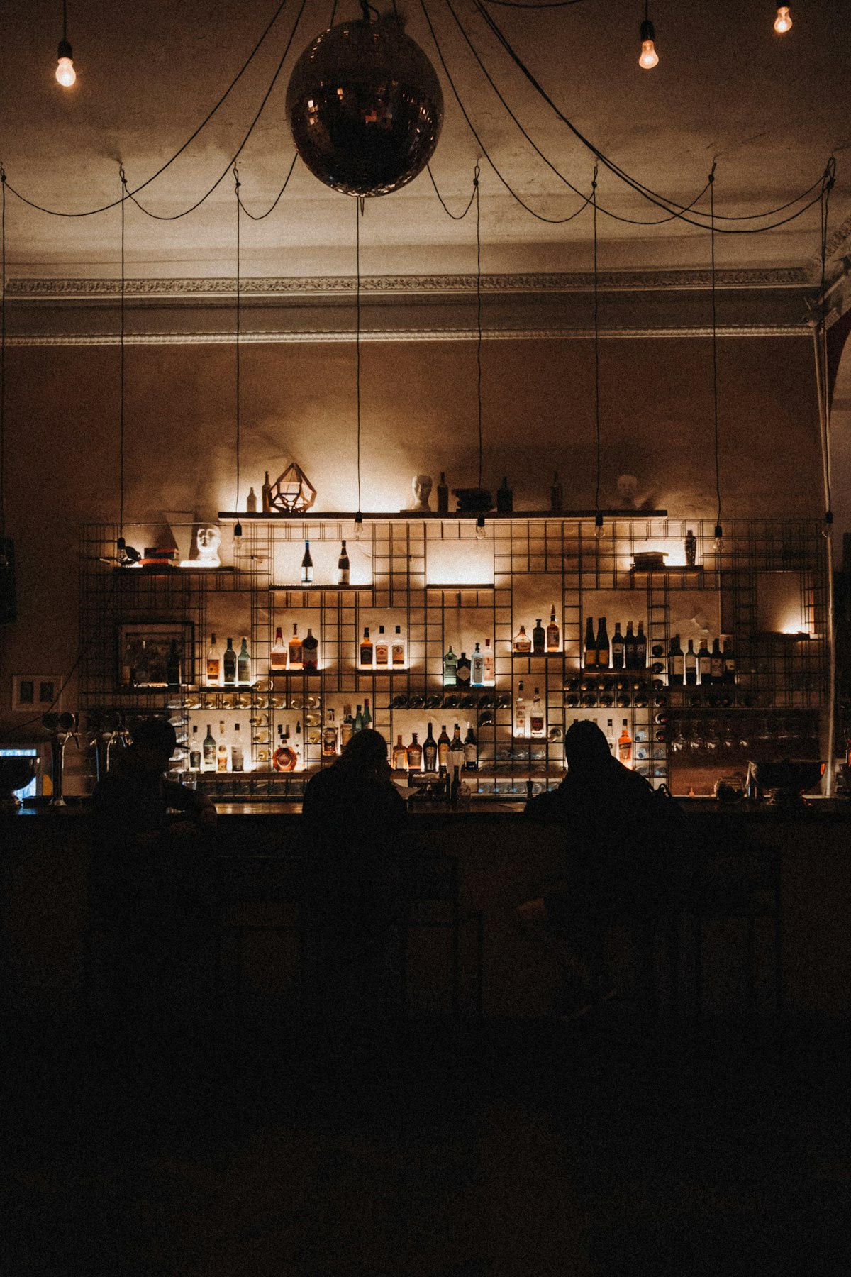 The back bar at Sable & Vine, bottles lit low