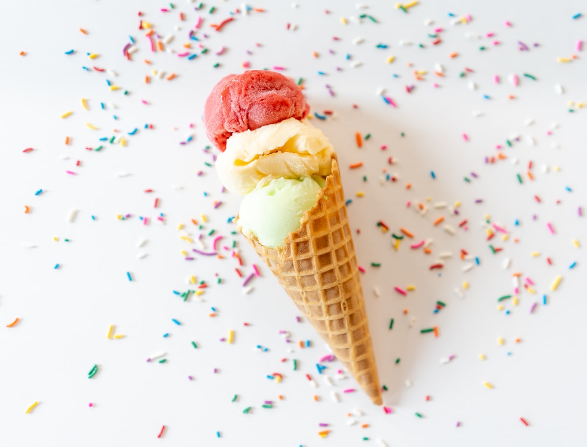 Triple scoop cone surrounded by rainbow sprinkles